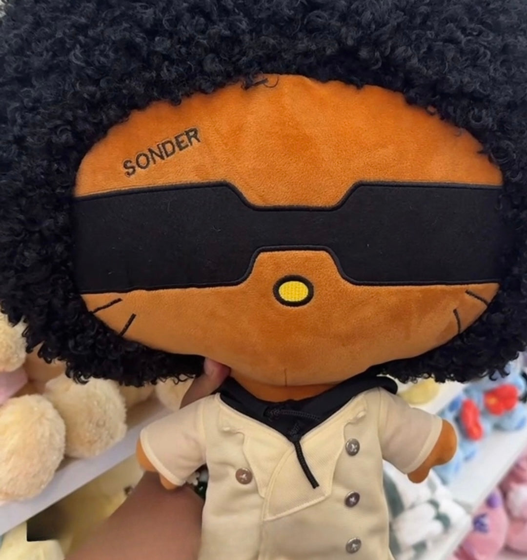 Close-up of SONDER Plush face, sunglasses, and afro detail