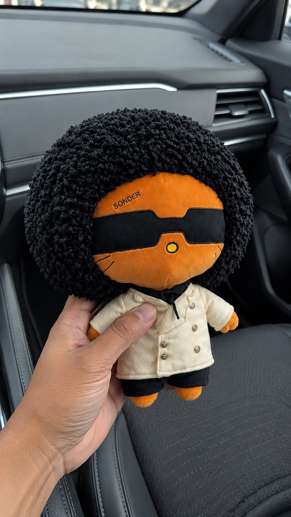 SONDER Plush held up close in a car interior