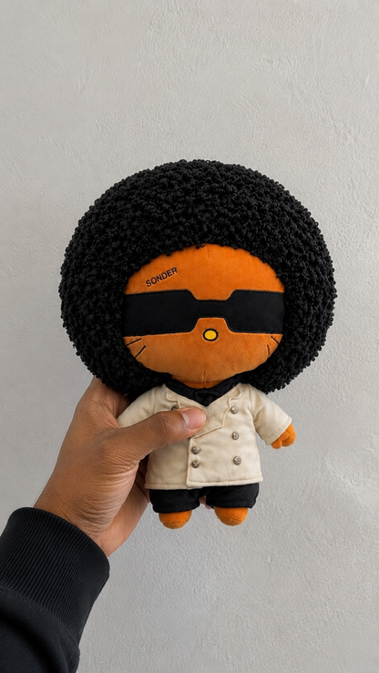 SONDER Plush held up close against a plain wall